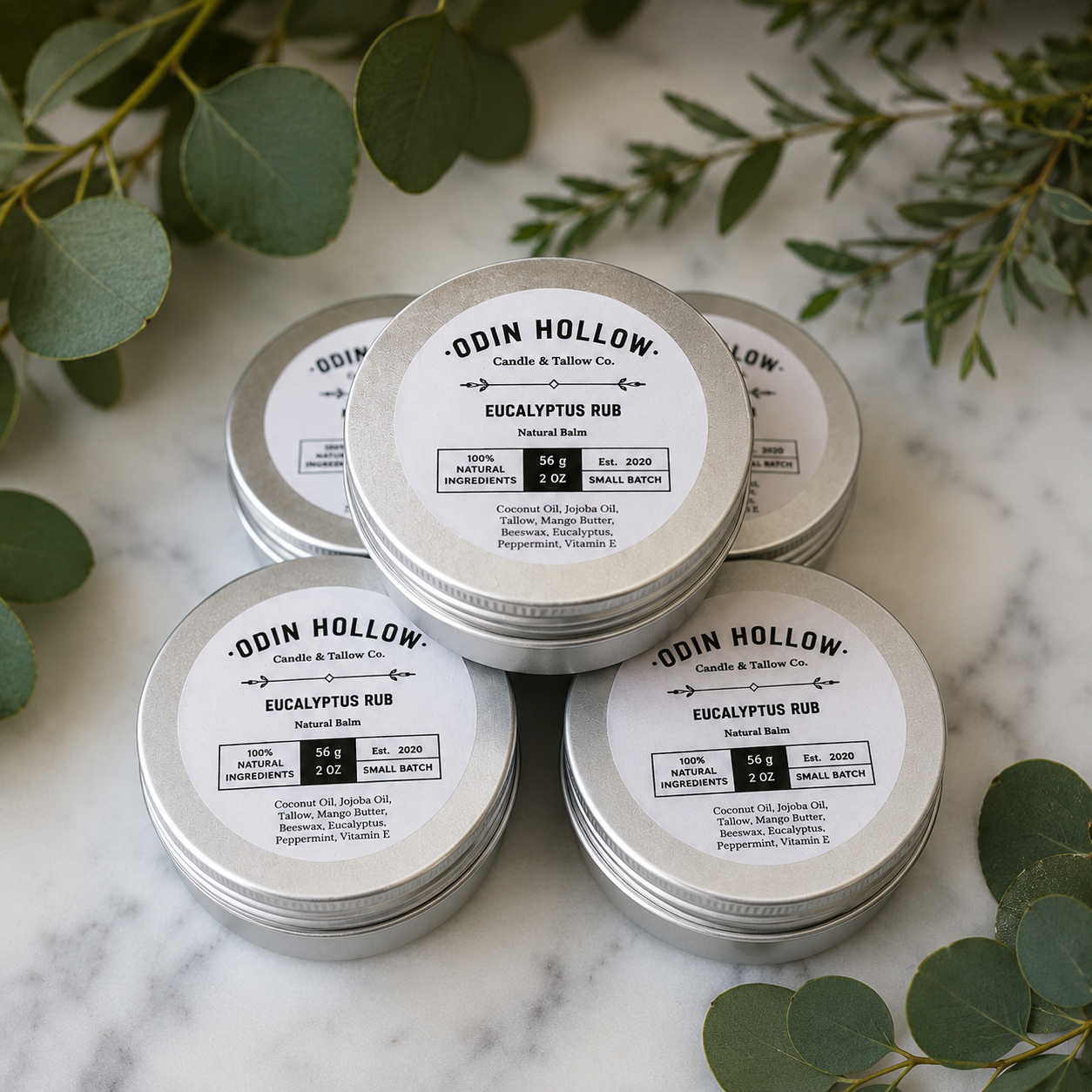 Silver tins labeled 'Odin Hollow' on a marble surface with green leaves.